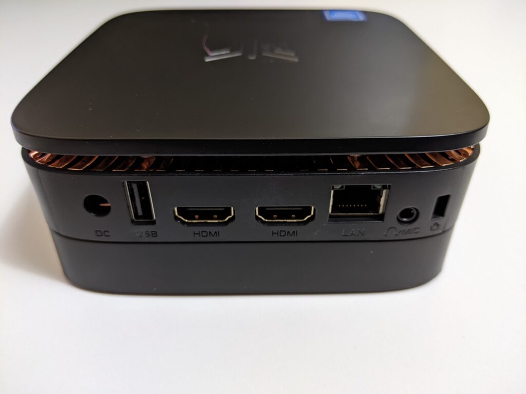 Image of the Kamrui AK1 Pro Mini PC from the side.  Image features power port, USB 2.0 port, 2x HDMI ports, Ethernet LAN port, audio + mic port and Kensington lock